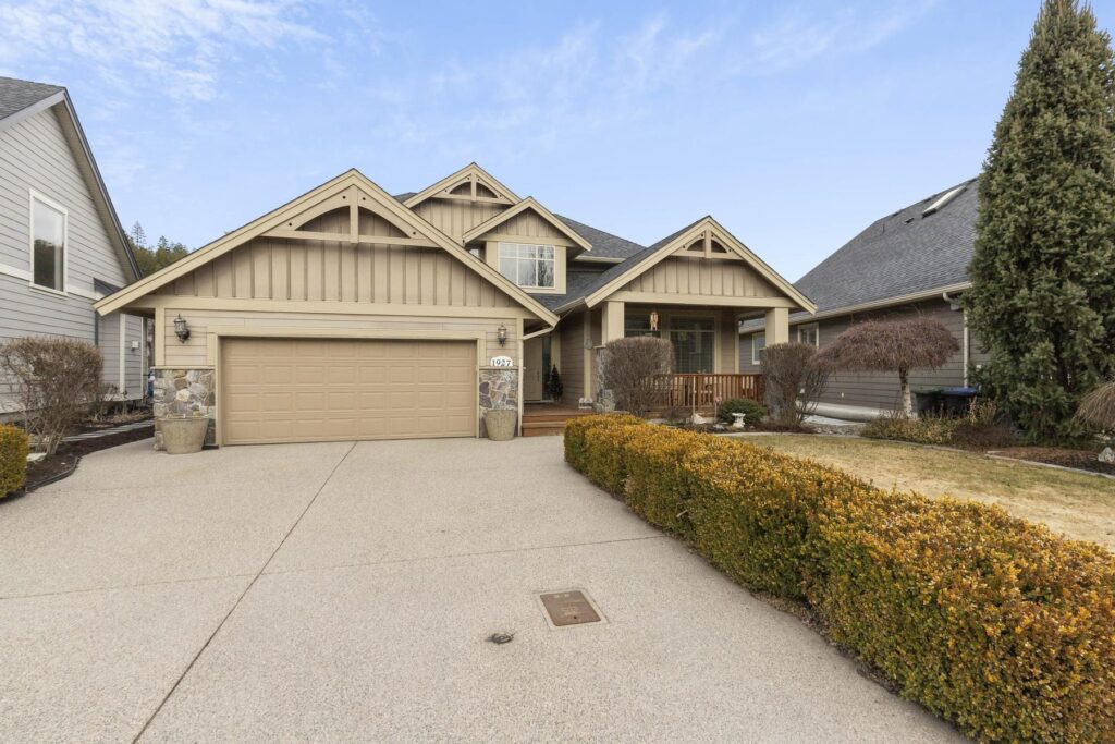 Front of a single-storey home with two gabled peaks, a double garage and a low hedge along the driveway.