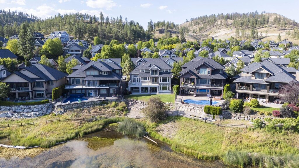 Aerial view of houses arranged around a small lake, with dry benchland hills rising behind them.