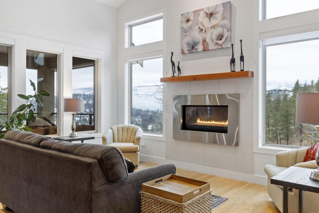 Living room with a linear gas fireplace, a dark sofa and tall windows looking out to the valley.