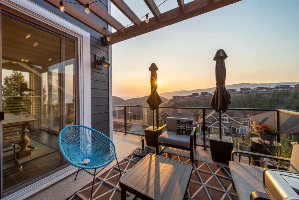 Deck seating and a low table beside sliding doors, lit by a low sun with hills in the distance.