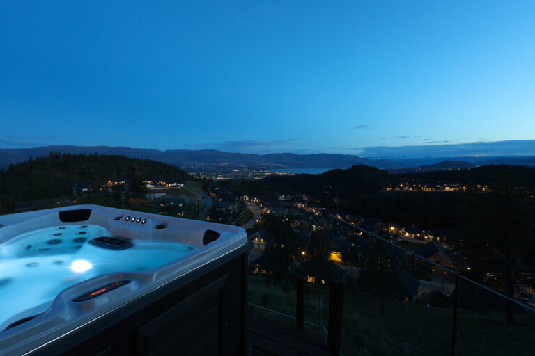 Kelowna hillside neighbourhood at dusk with city lights across the valley
