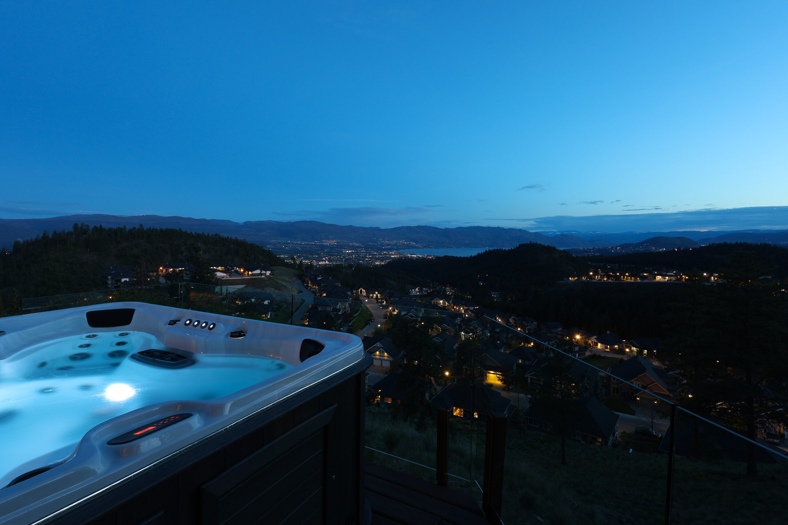 Kelowna hillside neighbourhood at dusk with city lights across the valley